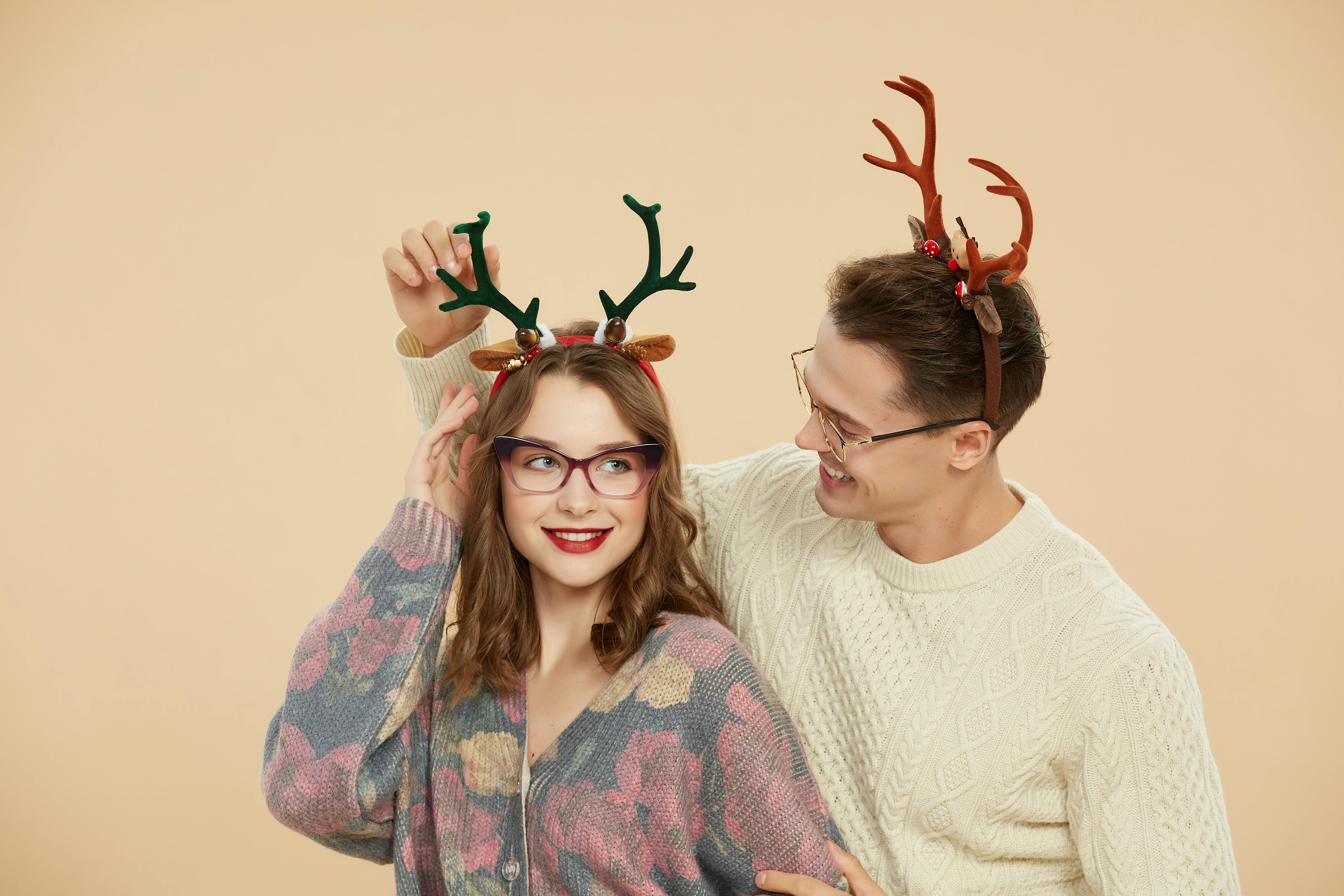 man and woman wearing reindeer antlers